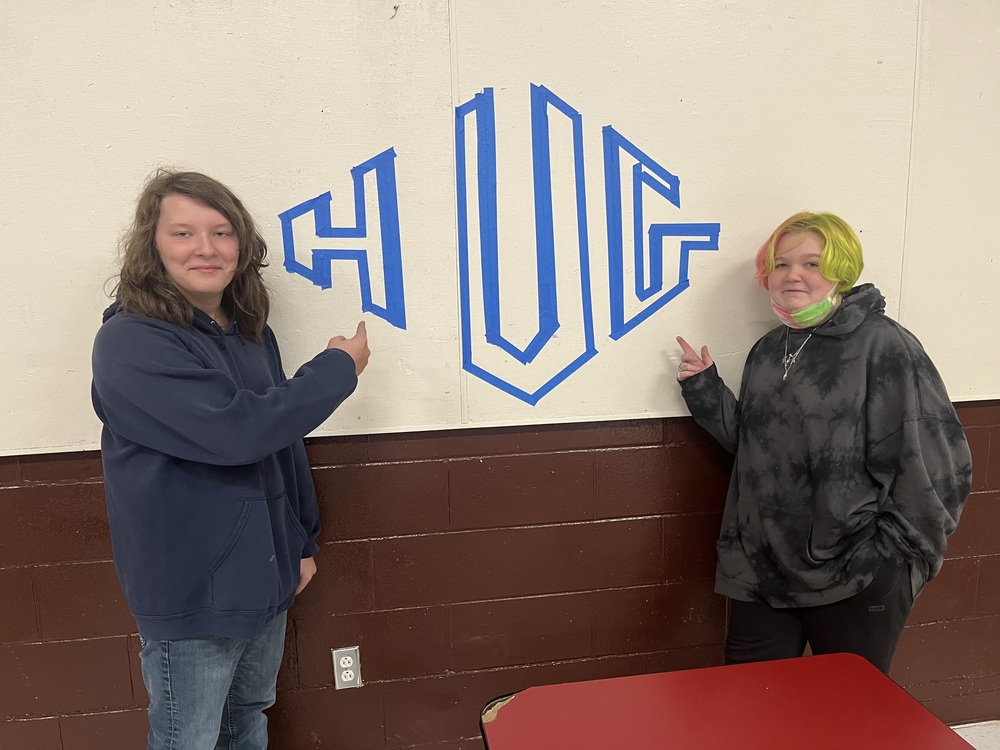 Students standing in front of the word HUG