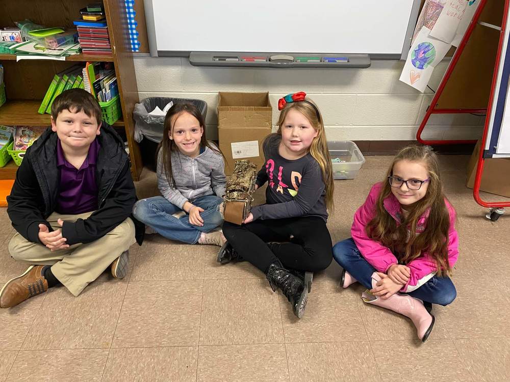 students holding models of Native American housing