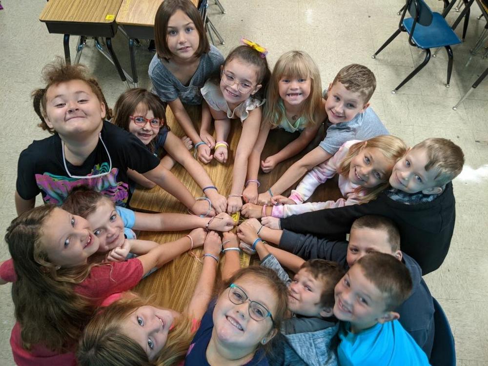Students in a circle with their hands together 