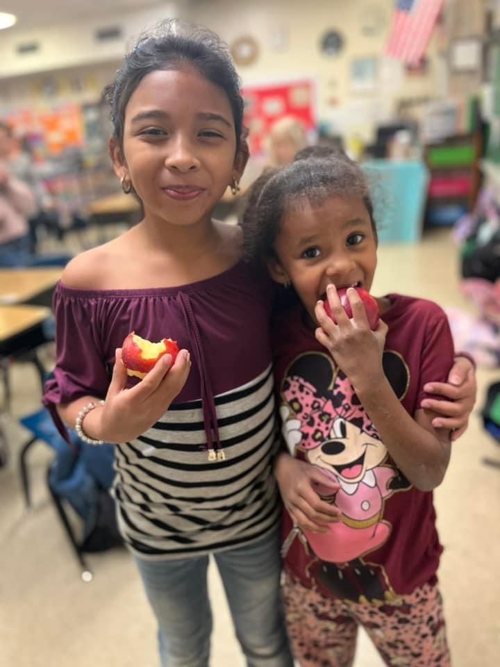 students taking a bite of an apple