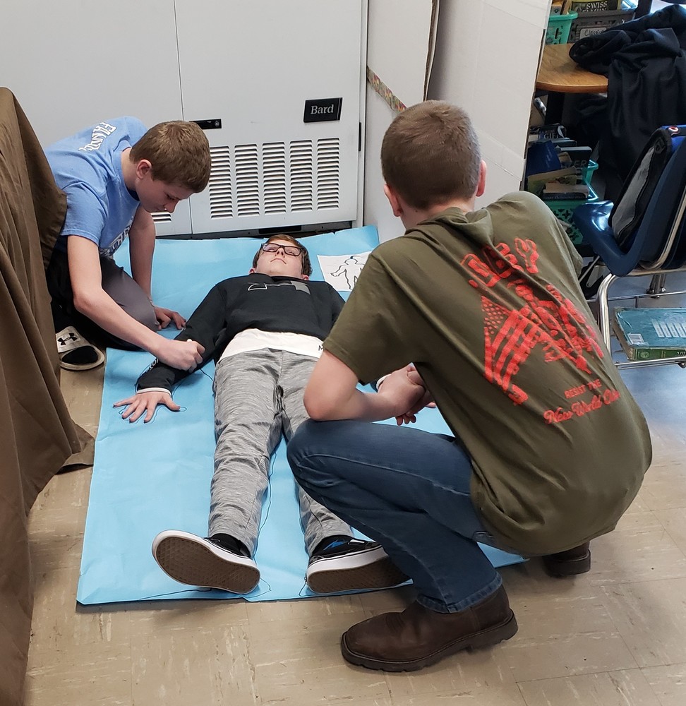 students tracing another student lying on the floor